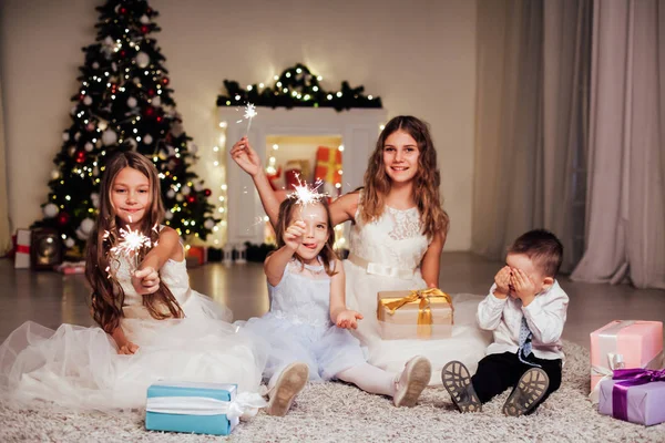 O menino e três meninas abrir presentes árvore de Natal ano novo grinalda — Fotografia de Stock