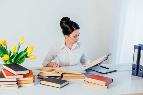 Mujeres en un traje de negocios detrás de una mesa con libros — Foto de Stock