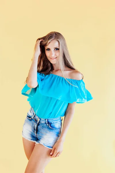 Ragazza bionda in un abito blu, su uno sfondo giallo — Foto Stock