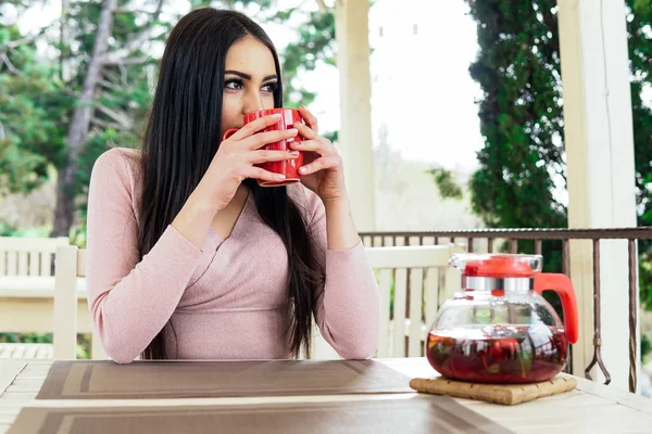 Girl drinking a hot drink in the outdoor restaurant — Stock Photo, Image