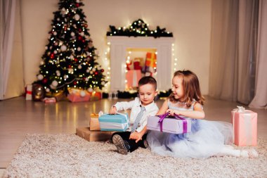 Küçük çocuk ve kız Noel hediyelerini açar Noel ağacı Yeni yıl arifesi aile kutlaması