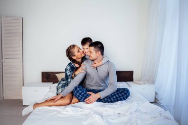 Anne baba ve oğul evde yatakta iyi bir ruh hali yatarken sabah