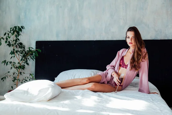 Hermosa mujer en ropa interior con una copa de vino en el dormitorio — Foto de Stock