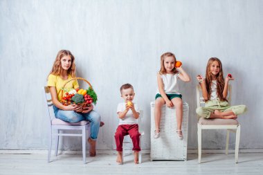 Çocuklar taze sebzelerle oturur sağlıklı meyve yerler.