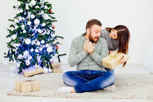 Man och hustru på julgranar erbjuder gåvor för det nya året — Stockfoto