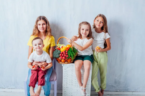 Niños se sientan con verduras frescas comiendo frutas saludables — Foto de Stock