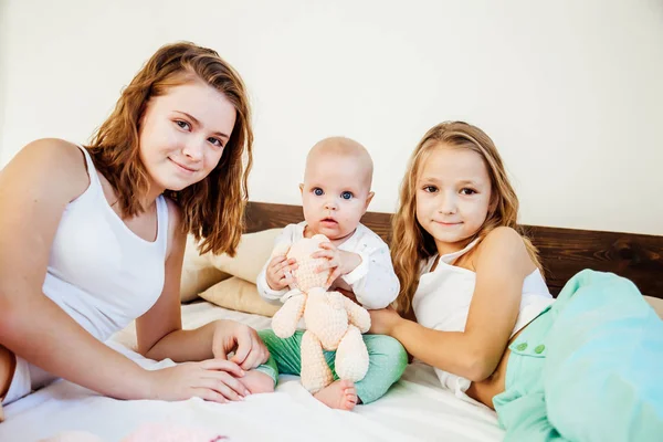 Tres niñas hermanas en la obra en el dormitorio por la mañana el amor —  Fotos de Stock