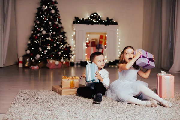 Menino e menina família abre presente de Natal ano novo luzes de férias guirlandas árvore de Natal — Fotografia de Stock