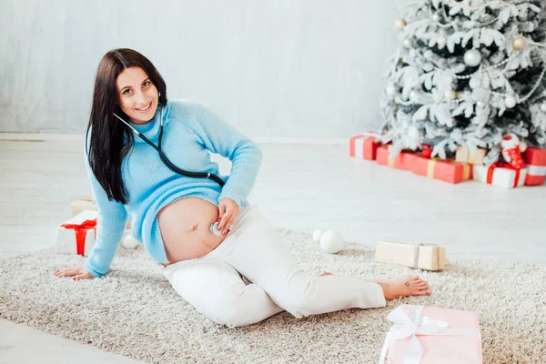 Krásná těhotná žena na vánoční stromeček s dárky na nový rok — Stock fotografie