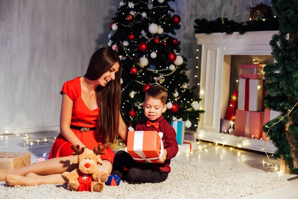 Мама с сыном украшают елку новогодние подарки гирлянда огни — стоковое фото