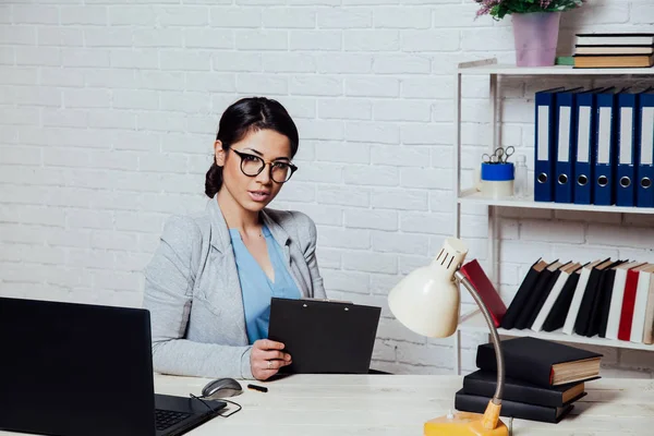 Деловая девушка сидит за компьютером в бумажных папках Office — стоковое фото