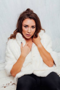 Kışın beyaz kürklü, saçları kıvırcık güzel bir kadının portresi.