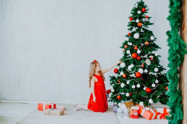 Kırmızı elbiseli küçük kız Noel hediyeleri yeni yıl tatili ile süslüdür