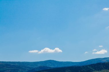 Yeşil bitkilerle ve mavi gökyüzüyle dağ manzarası