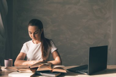 Kız sınava hazırlanıyor ve bir kitap okuyor.