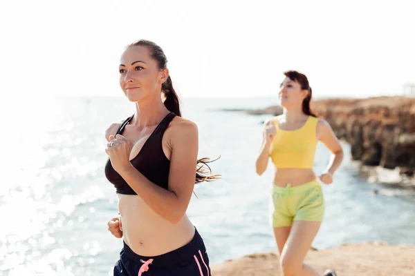 Girls on the run at the sea play sports — Stock Photo, Image