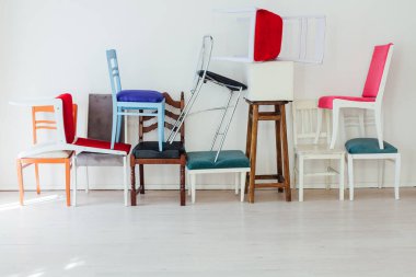 Birçok renkli sandalye beyaz odanın iç duvarına karşı durmaktadır.