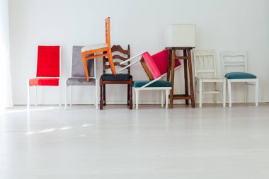 Birçok renkli sandalye beyaz odanın iç duvarına karşı durmaktadır.