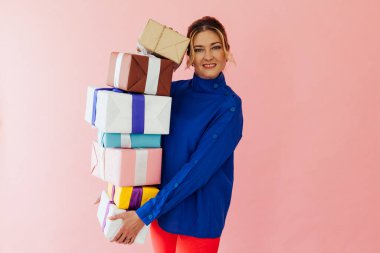 40 yaşındaki kadın, pembe üzerine bayram hediyeleri tutuyor.