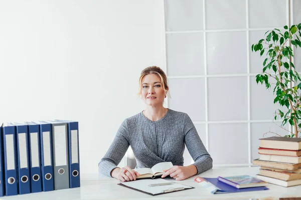 Mujer de negocios que trabaja en un escritorio en la oficina con la formación de libros — Foto de Stock