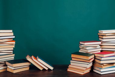 Okul kütüphanesinde öğretilecek bir sürü kitap yeşil arka planda.