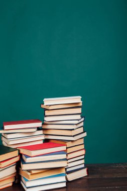 Okul kütüphanesinde öğretilecek bir sürü kitap yeşil arka planda.