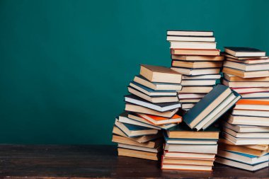 Okul kütüphanesinde öğretilecek bir sürü kitap yeşil arka planda.