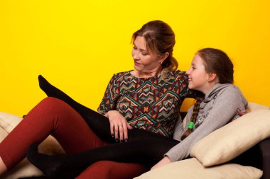 Anne ve kızı evde, aile kanepesinde oturuyor.