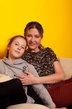 Anne ve kızı evde, aile kanepesinde oturuyor.