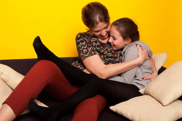 Mamá y su hija se sientan en casa en una habitación en el sofá de la familia — Foto de Stock