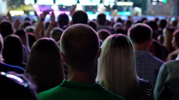 Толпа поддерживает людей, танцующих под музыку на концерте ночью — стоковое видео