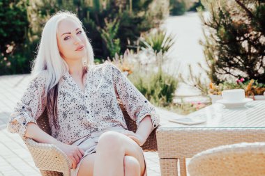 Güzel bir kız bir fincan çayla yeniden dükkanda oturuyor.