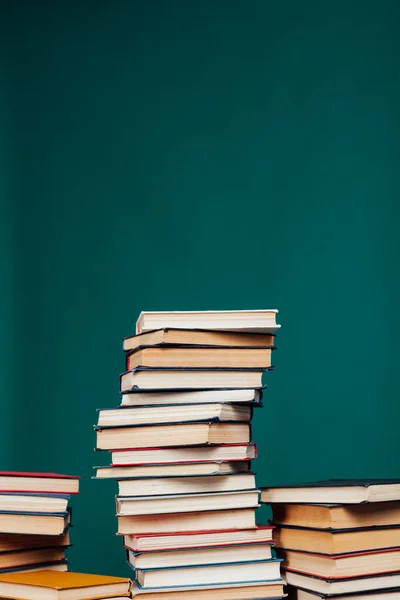 Viele Stapel Lehrbücher in der Universitätsbibliothek auf grünem Hintergrund — Stockfoto