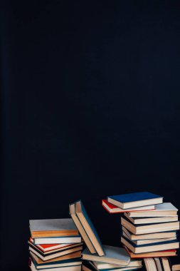 Üniversite kütüphanesinde siyah arkaplan üzerine bir sürü eğitim kitabı var.