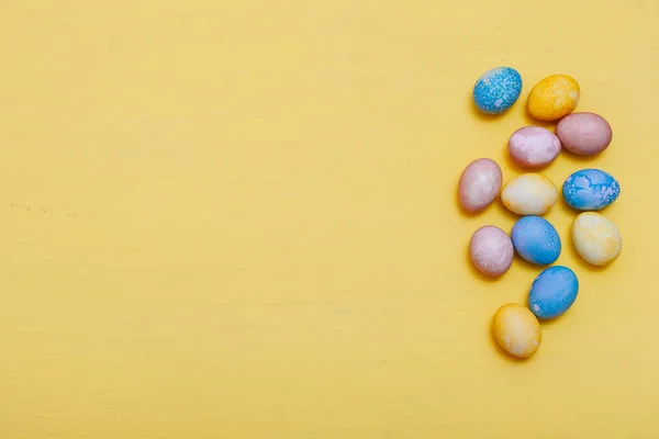 Ovos multicores para o feriado de Páscoa em um fundo amarelo — Fotografia de Stock