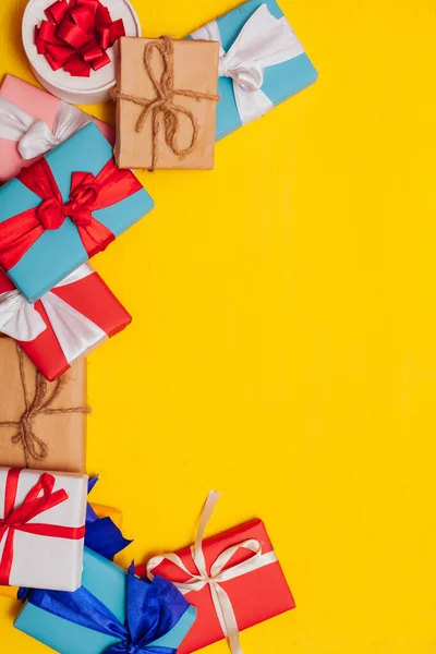 Muchos regalos multicolores para las vacaciones sobre un fondo amarillo —  Fotos de Stock