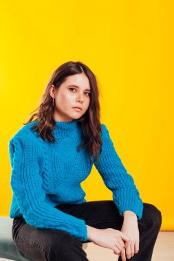 Güzel, modaya uygun, esmer, mavi kazaklı bir kadının portresi.