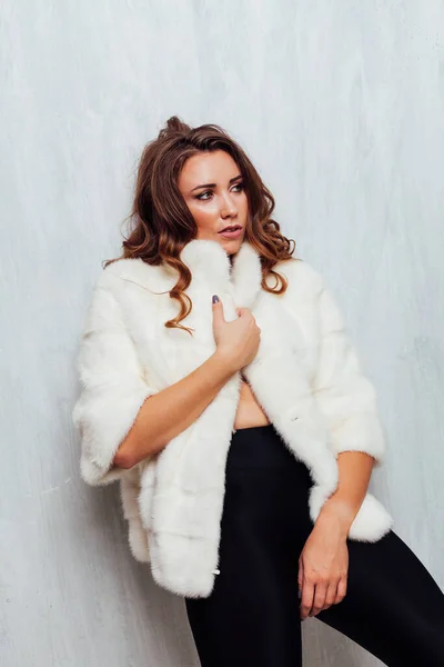 Portrait of a beautiful woman with curls in a white fur coat and black skirt — Stock Photo, Image