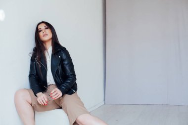 Güzel, modaya uygun, siyah deri ceketli esmer kadın.