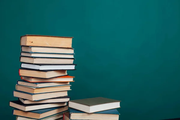 Un sacco di pile di libri didattici da insegnare nella biblioteca della scuola su uno sfondo verde — Foto Stock