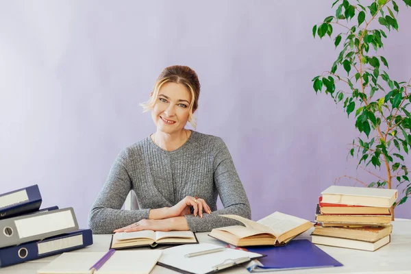 portrait of a businesswoman at a table with books and documents at work in the office