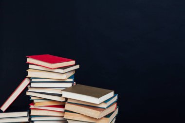 Üniversite kütüphanesinde siyah arka planda öğretecek bir sürü eğitim kitabı var.