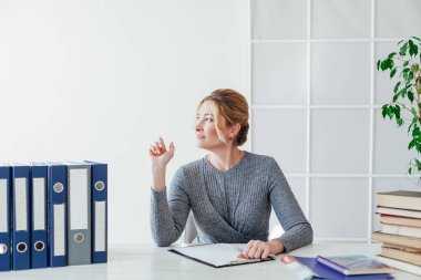 Ofiste kitap ve belgelerle dolu bir masada bir iş kadınının portresi.