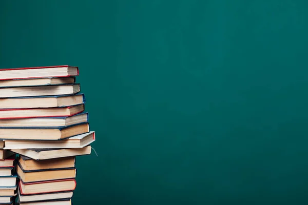 Veel stapels educatieve boeken om les te geven in de schoolbibliotheek op een groene achtergrond — Stockfoto