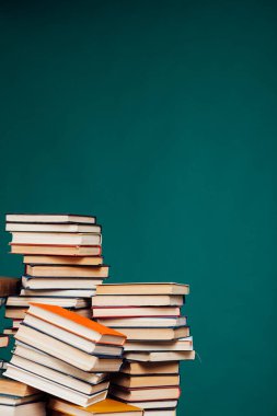Üniversite kütüphanesindeki sınavlar için yeşil bir arkaplan üzerine bir yığın eğitim kitabı