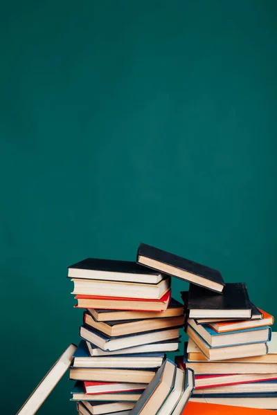 Molti pile di libri didattici per gli esami presso l'università in biblioteca su uno sfondo verde — Foto Stock