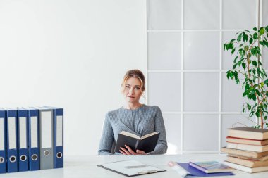 Ofiste kitapları olan güzel bir iş kadını portresi.