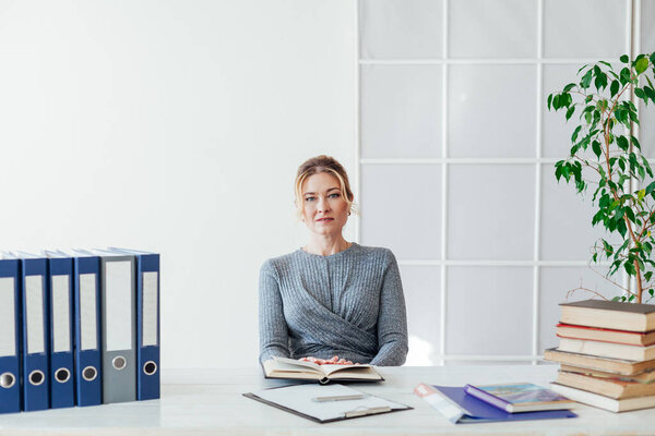 portrait of a beautiful business woman at a table with books at work in the office