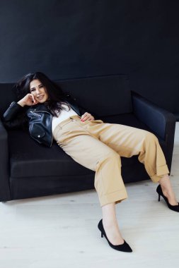 Siyah bir kanepede güzel, modaya uygun esmer bir kadının portresi.