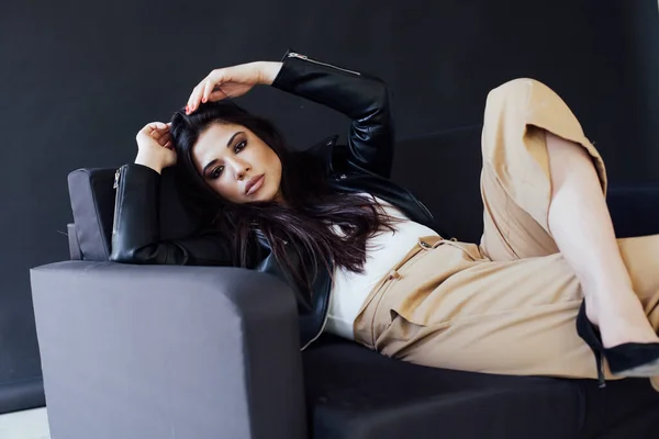 Portret pięknej orientalnej brunetki na czarnej sofie — Zdjęcie stockowe